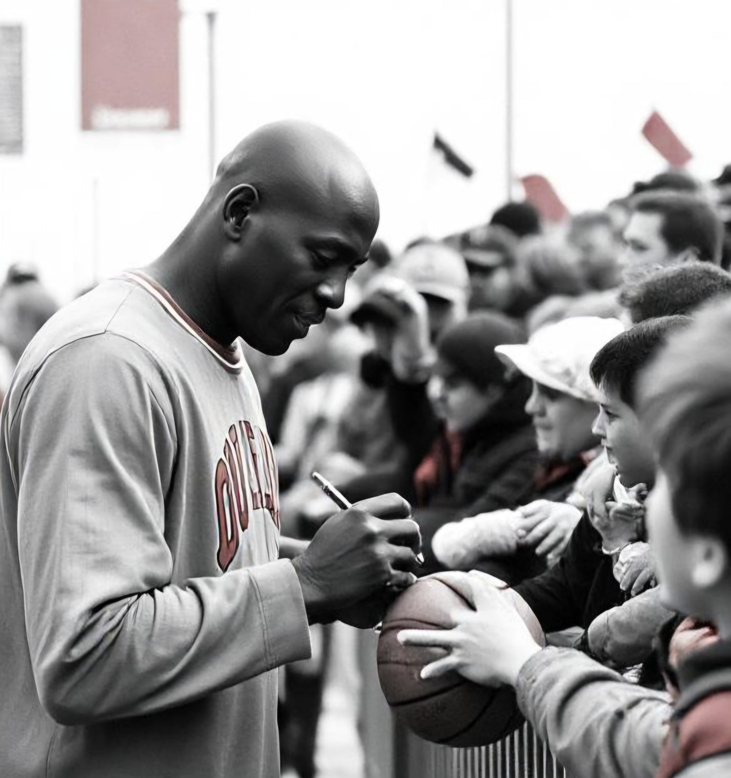 Black and white photo of Michael Jordan autographing basketball for boy